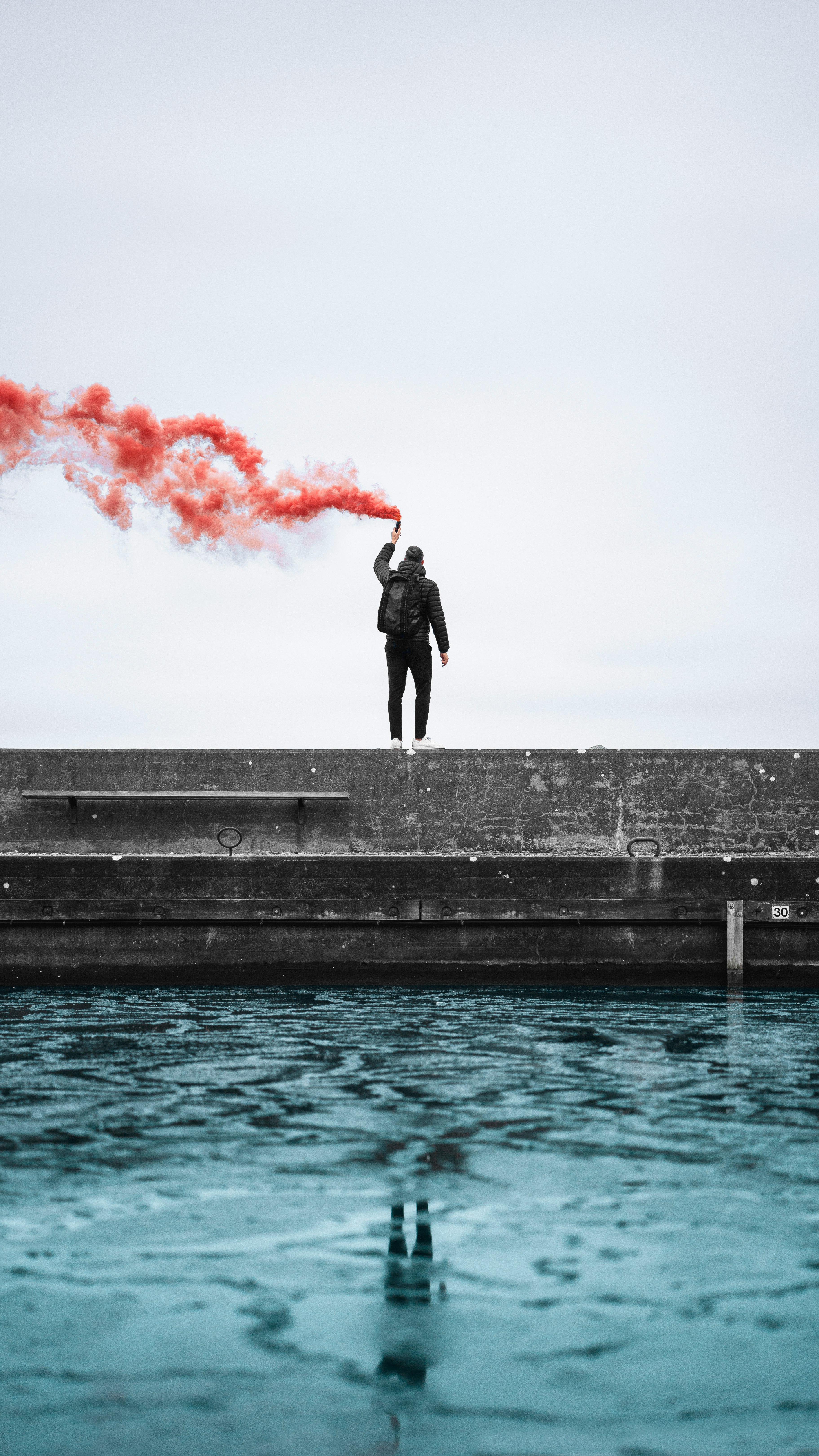 standing man holding lighted flare during daytime